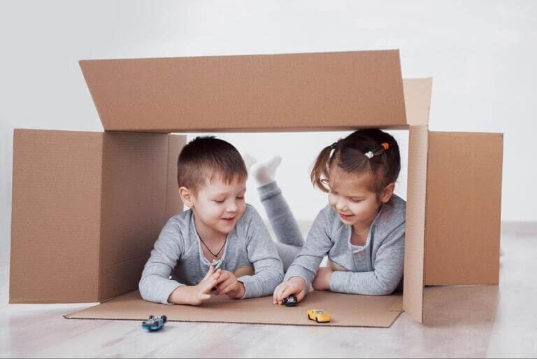 Мальчик и девочка играют в картонной коробке