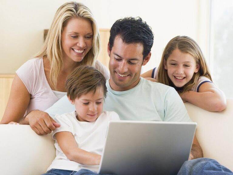 Мама, папа, сын и дочь смотрят в ноутбук