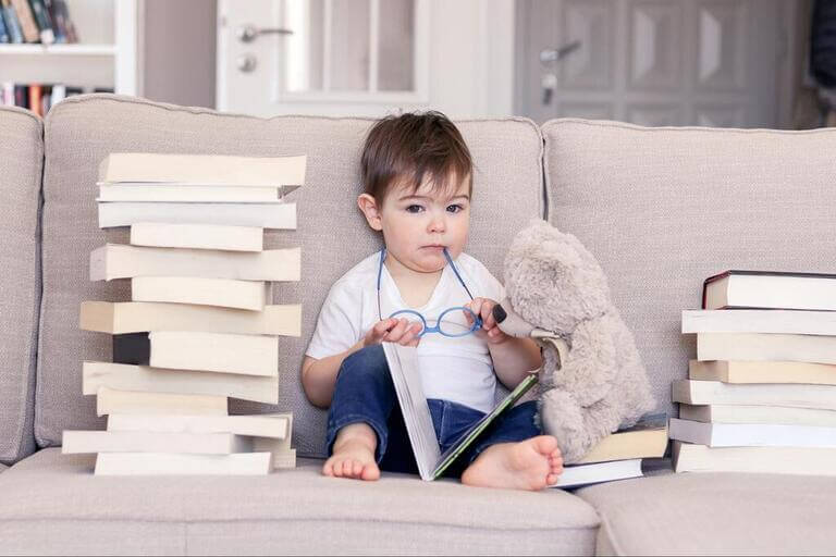Симпатичный умненький ребёнок с книжками и игрушкой